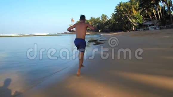 穿蓝色短裤的肌肉男在海滩上跑步视频的预览图