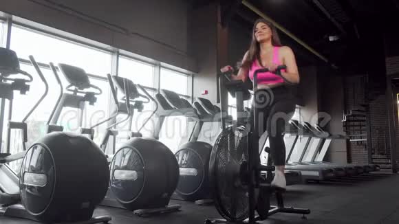 漂亮的快乐加上身材魁梧的女人骑着自行车在健身房锻炼视频的预览图