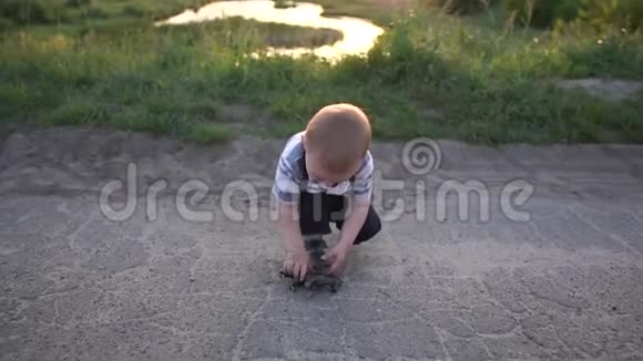 日落时分一个金发小男孩在大自然中玩一个马玩具动作缓慢视频的预览图