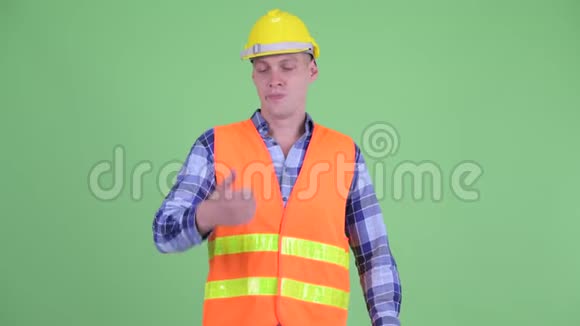 困惑的年轻人建筑工人在竖起大拇指和竖起大拇指之间做出选择视频的预览图