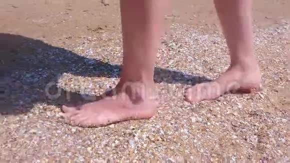 赤脚的女人在沙滩上走在贝壳上让大自然的脚按摩视频的预览图
