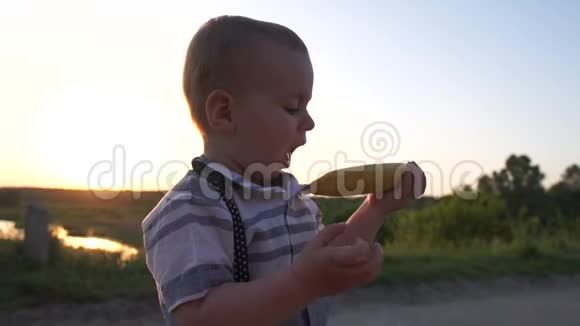 一个可爱的男孩在田里的嘴里拿着一根未剥皮的香蕉动作缓慢视频的预览图