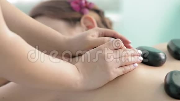 女性按摩师用热石疗法慢动作治疗女性背部视频的预览图