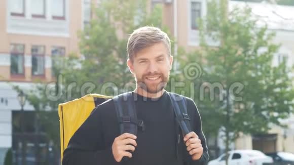 带黄色袋子的快递员显示手势好的一个带背包的留胡子的人做了一个积极的手势和微笑交货视频的预览图