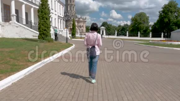 一位穿着粉红色衬衫和蓝色裤子的中年妇女在这个历史遗址上走来走去视频的预览图