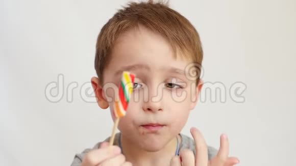 一个小男孩正在吃一根棍子上的亮糖一根棒棒糖视频的预览图