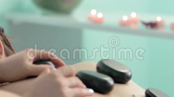 女性按摩师用热石疗法慢动作治疗女性背部视频的预览图