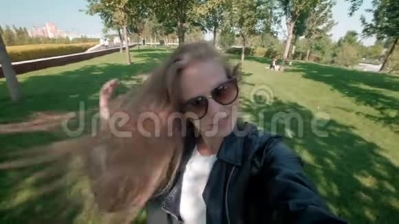 公园里的女学生穿着皮夹克的迷人女孩漫步在秋天公园在镜头前拍摄自己的照片视频的预览图