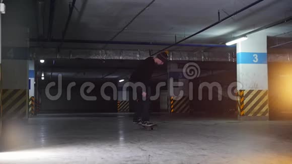 地下停车场一个年轻人在玩滑板训练他的踢腿技巧视频的预览图