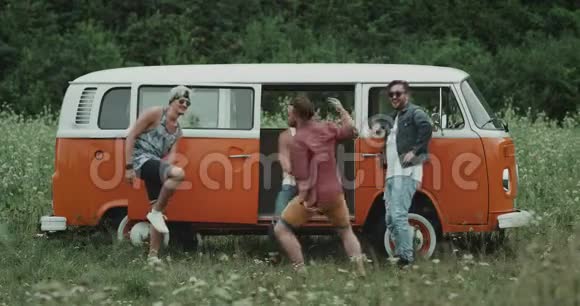 一群年轻时尚的小伙子在一辆复古的公共汽车前一起野餐跳舞和放松玩得很开心视频的预览图