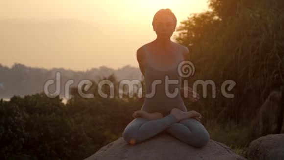 女孩坐在帕德马萨纳在圆石上日出慢动作视频的预览图