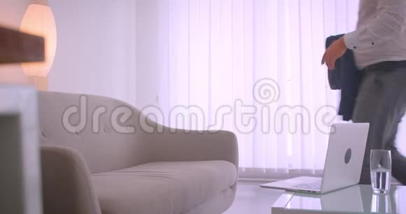 成人疲惫的白种人商人用笔记本电脑在公寓里悠闲地坐在沙发上的特写画像视频的预览图