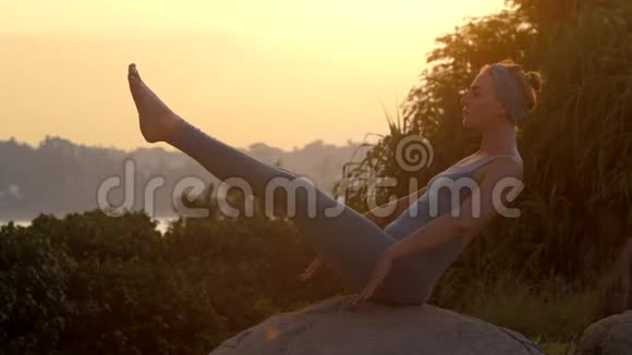 瑜伽老师在日出时在石头上展示纳瓦萨纳慢动作视频的预览图
