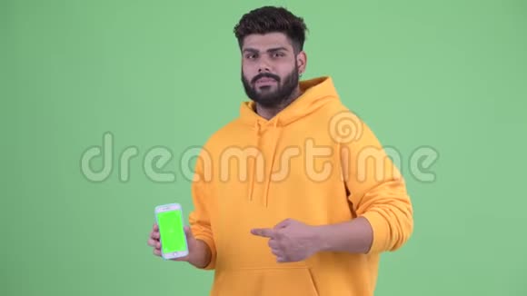 年轻体重超重留着胡须的印度男人带着手机竖起大拇指视频的预览图
