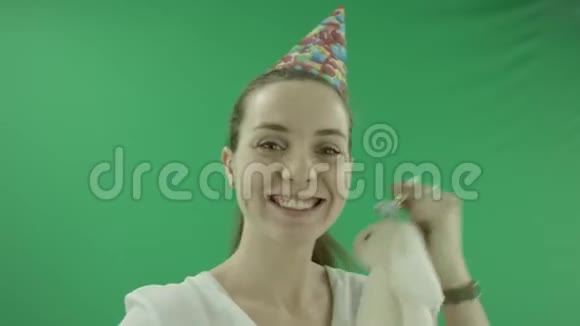 令人惊讶的兴奋的女人正在笑在生日帽与玩具和塑料口哨与全息纸管她穿着视频的预览图