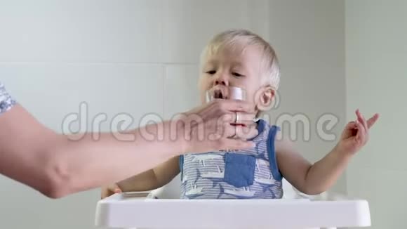 可爱的金发幼儿喝着妈妈给他的红色果汁视频的预览图