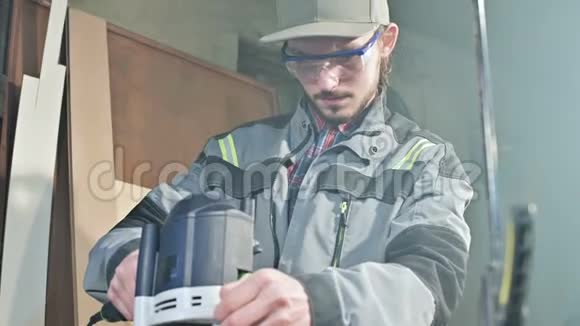 木工在家庭车间用手动电动切割机进行手工操作的手整理木制部件视频的预览图