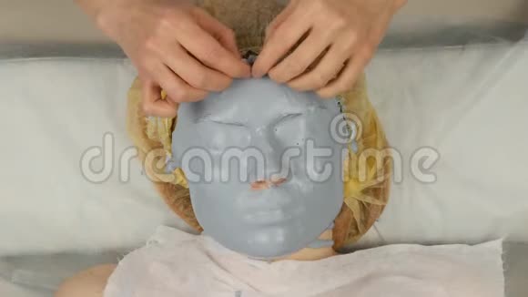 美容师在水疗沙龙为女人的脸摘下泥面膜面部年轻化程序水疗4K视频的预览图
