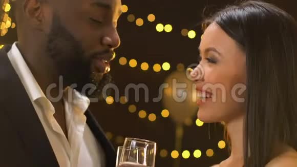 自信的黑人男子与亚洲女士调情聊天喝香槟视频的预览图