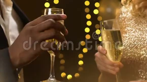 多种族夫妇在新年聚会上喝着香槟灯光闪烁特写镜头视频的预览图