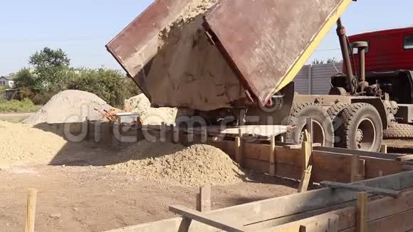 卡车从拖车上卸下沙子新建地基房屋的土方工程视频的预览图