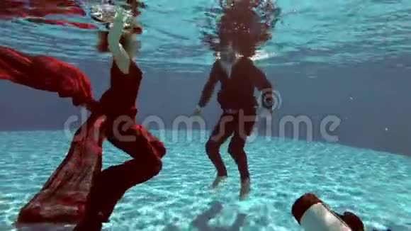 水下摄影师把新娘和新郎穿着婚纱在水池底部的水下拍摄视频的预览图