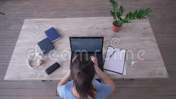 学生女孩在键盘上输入文字时使用笔记本电脑并在电子学习过程中在桌旁的剪贴板上写笔记视频的预览图