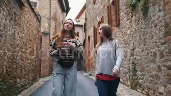 年轻迷人的女人走在狭窄的街道上自拍视频的预览图