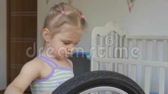 一个小女孩坐在孩子们房间里玩自行车转动轮子视频的预览图