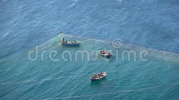 在蔚蓝的大海上乘坐三艘船的渔民从渔网中获取猎物视频的预览图