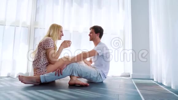 幸福的微笑情侣坐在地板上喝着早间咖啡视频的预览图
