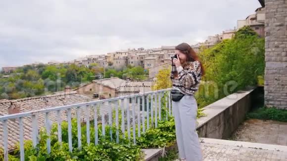 迷人的年轻女子站在阳台上拍摄绿色景观视频的预览图
