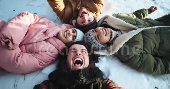 一群兴奋的朋友躺在森林中央的雪层上享受在一起的时光组成了一个视频的预览图