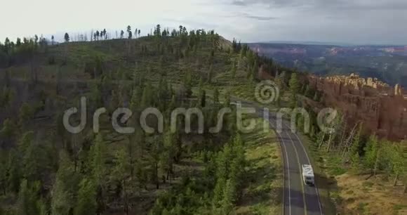 无人机在高速公路上行驶的白色拖车和峡谷底部的松林上空盘旋视频的预览图