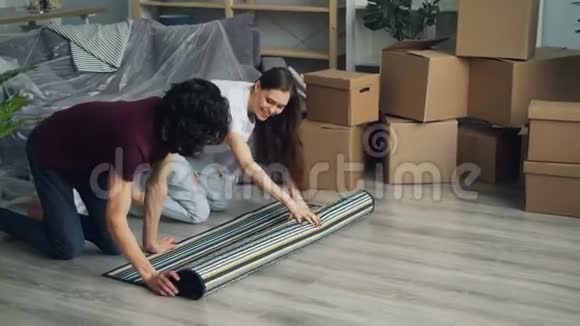 男人和女人一起搬到新公寓后在地板上铺上地毯视频的预览图