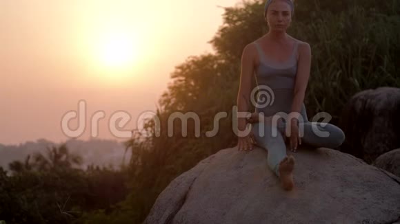 日出时分女人在巨大的岩石上健身视频的预览图