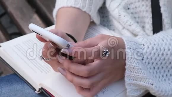 用智能手机用打开的书合上女人的手视频的预览图
