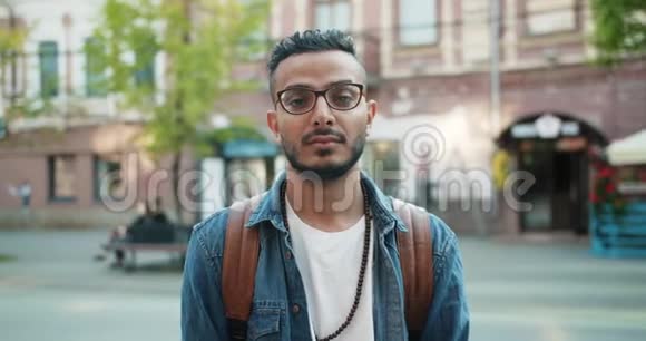 戴眼镜的阿拉伯帅哥站在户外严肃的脸上的肖像视频的预览图