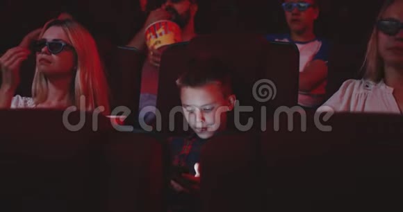 在电影院里用智能手机的男孩视频的预览图