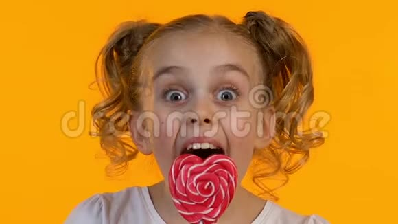 非常快乐的小女孩享受心形棒棒糖的味道特写视频的预览图