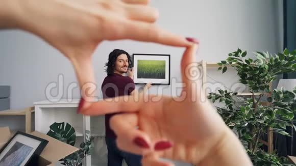 女人帮助男人在房间里选择拍照的位置做手势和说话视频的预览图