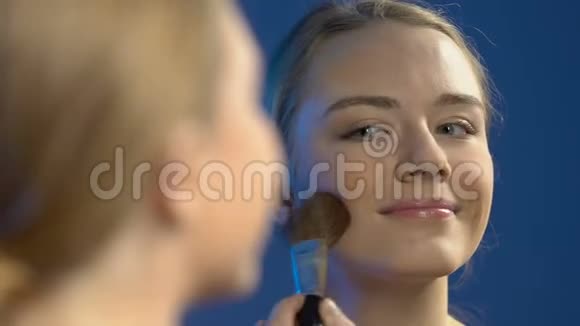 微笑的女孩涂着晚妆给镜子送气吻虚荣视频的预览图