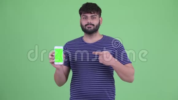 年轻体重超重留着胡须的印度男人带着手机竖起大拇指视频的预览图