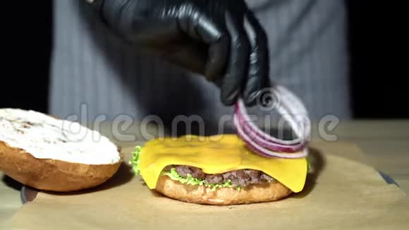 厨师准备汉堡把男人的手举起来把洋葱圈堆成汉堡包视频的预览图