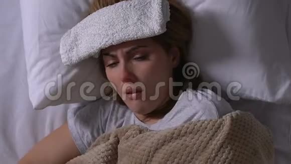 病妇额头上有毛巾躺在床上咳嗽流鼻涕流感视频的预览图