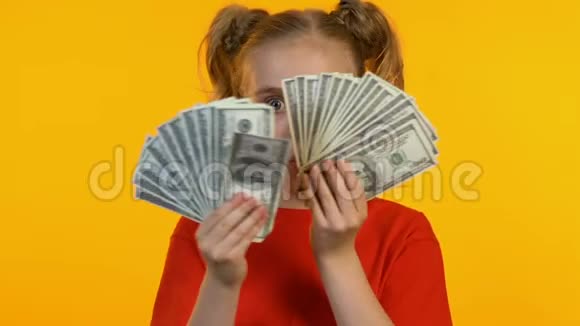 开朗的小女孩在镜头前展示着一束钱微笑着第一次收入视频的预览图