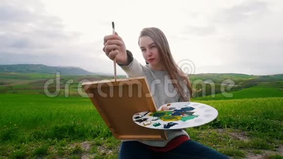 一位身材矮小的年轻女子坐在草地上画着测量图像比例视频的预览图