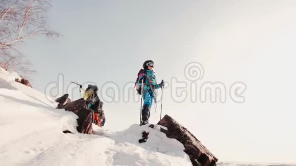 年轻的登山者全副武装手里拿着滑雪杆站在山顶上欣赏风景视频的预览图