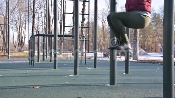女孩腿在开放区域进行健身女人摇动悬挂在水平杆上的压力视频的预览图