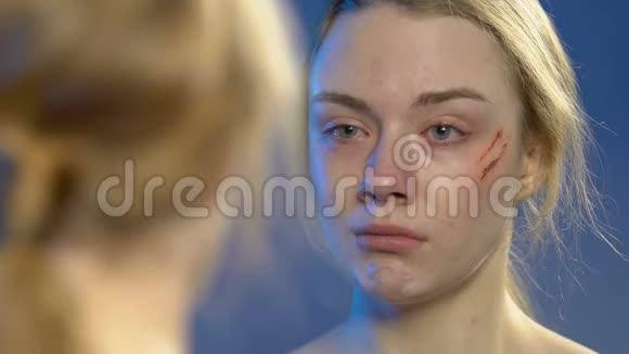 一个脸受伤的少女看着镜子的倒影深深地哭着视频的预览图